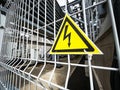 Danger Sign High voltage in a yellow triangle on a metal grid Royalty Free Stock Photo