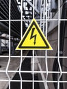 Danger Sign High voltage in a yellow triangle on a metal grid Royalty Free Stock Photo