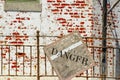 Danger sign on rusty banister on grunge brick wall