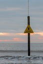 Danger Sinking Mud sign in front of waves and sunset