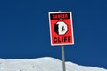 Danger steep cliff sign on snow cape mountain summit