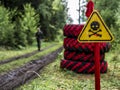 a danger zone sign in the forest next to the road, warning that the area is mined. Wartime concept. Royalty Free Stock Photo