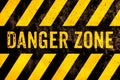 Danger zone warning sign text with yellow and black stripes painted over concrete wall surface facade cement texture background