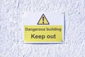 Dangerous building keep out warning caution sign on white wall at construction building site Royalty Free Stock Photo