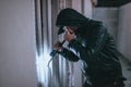 Hooded man with flashlight entering into house Royalty Free Stock Photo