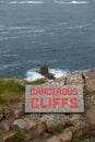 Dangerous cliffs sign in red writing Royalty Free Stock Photo