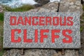 Dangerous cliffs sign in red writing Royalty Free Stock Photo
