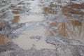 Dangerous destroyed roadbed. Big pothole filled with water.