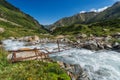 Dangerous dilapidated rusty metal bridge over a turbulent mountain river on a sunny day Royalty Free Stock Photo