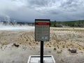 Dangerous Ground Sign in Front of an Active Geyser with Rising Steam in Yellowstone Royalty Free Stock Photo