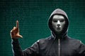 Dangerous hacker over abstract digital background with binary code. Obscured dark face in mask and hood. Data thief Royalty Free Stock Photo
