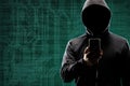 Dangerous hacker with a smartphone gadget over digital background with binary code. Obscured dark face in mask and hood