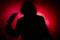 A dangerous hooded man standing in the dark and holding a knife. Face can not be seen. Committing a crime concept. Selective focus Royalty Free Stock Photo