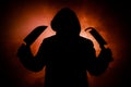 A dangerous hooded man standing in the dark and holding a knife. Face can not be seen. Committing a crime concept. Selective focus Royalty Free Stock Photo