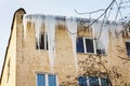 Dangerous icicles on the eaves of houses. Ice blocking windows and endangering people Royalty Free Stock Photo