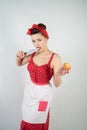 Dangerous pin up girl housewife in red vintage polka dot dress stands with a huge kitchen knife in her hands and angrily rejoices