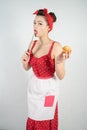 Dangerous pin up girl housewife in red vintage polka dot dress stands with a huge kitchen knife in her hands and angrily rejoices