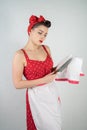 Dangerous pin up girl housewife in red vintage polka dot dress stands with a huge kitchen knife in her hands and angrily rejoices