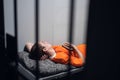 A dangerous prisoner in a cell rests and sleeps in a solitary cell on a bunk in an orange robe.