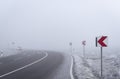 Dangerous road curve and warning signs in a dense mist Royalty Free Stock Photo