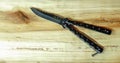 Dangerous sharp butterfly knife on a wooden background. Black butterfly knife on a wooden Board. Royalty Free Stock Photo