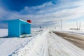 Dangerous snowing road with empty bus stop and road signs in rural for driving cars and public transport during blizzard