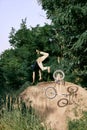 Dangerous sport. Young man riding on hill in park, forest on bmx bike, doing tricks and falling down Royalty Free Stock Photo