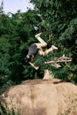 Dangerous sport. Young man riding on hill in park, forest on bmx bike, doing tricks and falling down Royalty Free Stock Photo