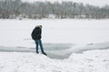 Dangerous thin ice. Man takes risk to step on frozen river surface in winter. Caution. unsafe water