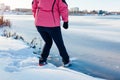 Dangerous thin ice. Woman takes risk to step on frozen river surface in winter. Caution, unsafe water, drop possibility