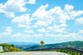 Dangerous twisty road through Colorado mountains showing cliff and valley far below and road sign by guard rail under beautiful Royalty Free Stock Photo