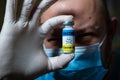 The dangers of coronavirus vaccination. Harmful side effects concept. Doctor holds a vial of vaccine with a toxicity warning sign