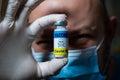 The dangers of coronavirus vaccination. Harmful side effects concept. Doctor holds a vial of vaccine with a toxicity warning sign