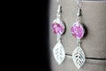 Dangle resin earrings with rose petals on a dark background