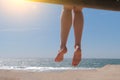 Dangling bare female feet sitting on beach.