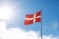 Danish flag waving on the blue sky sun glare background. Royalty Free Stock Photo