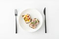 Danish smorrebrod open sandwiches on white plate, fork and knife on white background