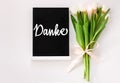 Danke thank you in German card sign on black chalkboard with tulip flowers on white background flat lay, greeting text