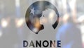 Danone logo on a glass against blurred crowd on the steet. Editorial 3D rendering