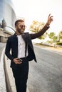 Dapper Indian Arabic businessman waving down taxi cab e-hailing