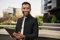 Dapper smiling indian muslim businessman holding digital tablet outside