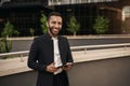 Dapper smiling indian muslim businessman holding tablet outside