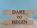 Dare to begin symbol. Brick blocks with words \'Dare to begin\'. Beautiful blue background, wooden table.