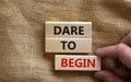 Dare to begin symbol. Wooden blocks with words `Dare to begin`. Beautiful canvas background, businessman hand. Business, dare to