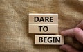 Dare to begin symbol. Wooden blocks with words `Dare to begin`. Beautiful canvas background, businessman hand. Business, dare to