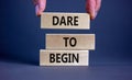 Dare to begin symbol. Wooden blocks with words `Dare to begin`. Beautiful grey background, businessman hand. Business, dare to