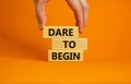 Dare to begin symbol. Wooden blocks with words `Dare to begin`. Beautiful orange background, businessman hand. Business, dare to