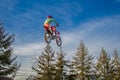 person on bike doing stunts in air above trees outside of a park