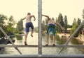 Daring young boys jumping off a bridge into the river. View from behind.