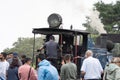 Crowd of people standing looking at the toy train driver on the small steam engine at batasia loop in Darjeeling